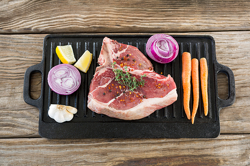Sirloin chop and ingredients on grill tray against wooden background