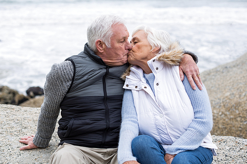 Senior man kissing senior woman on beach