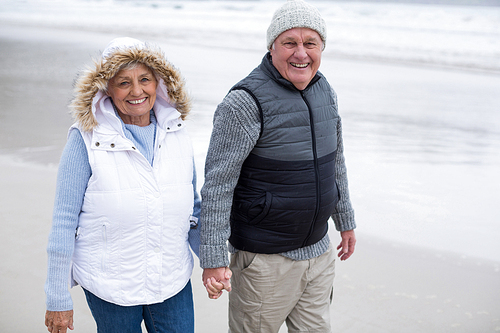 Senior couple walking toward the ocean while holding hands at beach