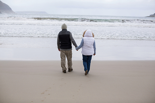 Rear view of senior couple walking together on the beach