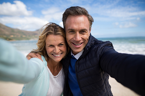 Portrait of mature couple smiling at camera on the beach