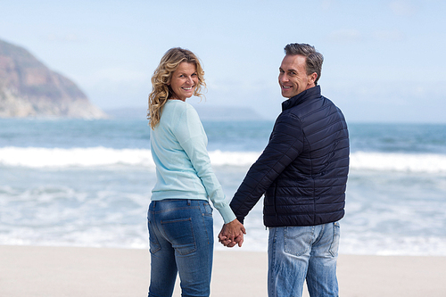 Portrait of smiling couple standing with holding hands on the beach