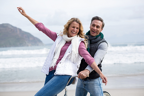 Happy mature couple riding bicycle on the beach