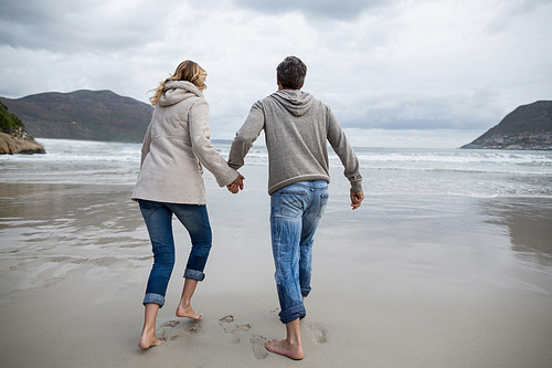 Rear view of mature couple running on the beach
