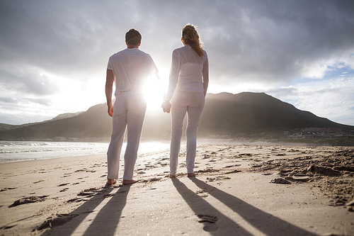 Rear view of standing with couple holding hands on the beach