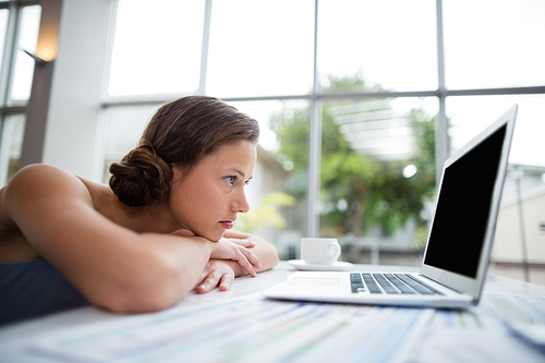 Businesswoman leaning on desk and looking at laptop at conference centre