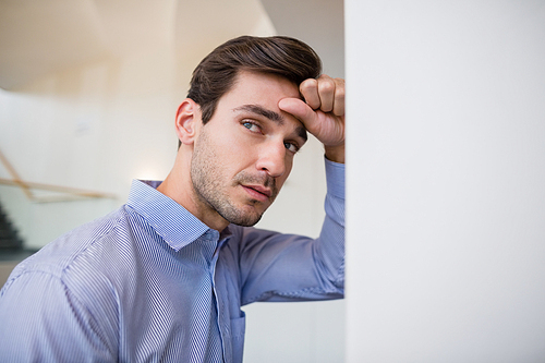 Worried businessman with hand on head leaning on wall at conference centre