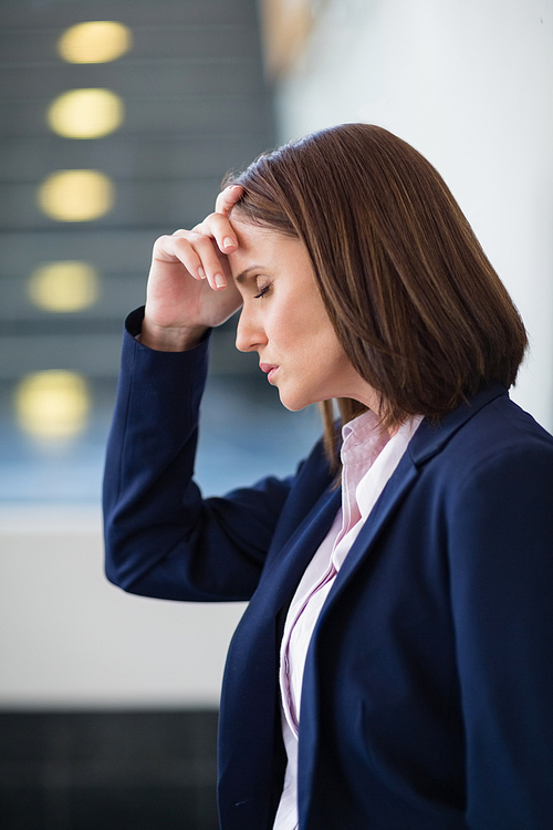 Worried businesswoman with hand on head at conference centre