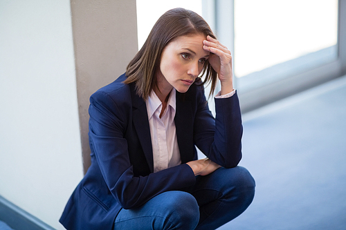 Worried businesswoman crouching on floor at conference centre