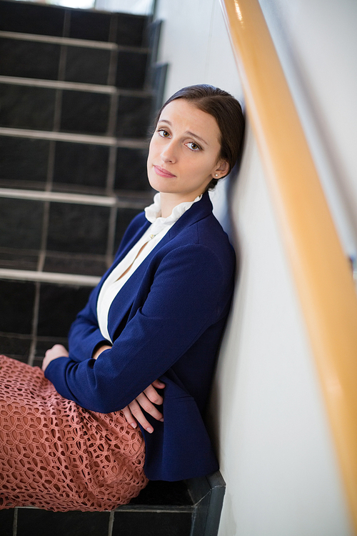 Portrait of worried businesswoman sitting on steps at conference centre