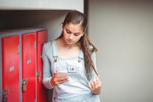 Schoolgirl using mobile phone in locker room at school