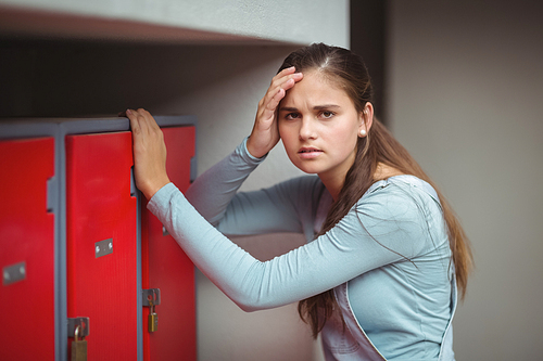 Portrait of sad schoolgirl standing in locker room at school