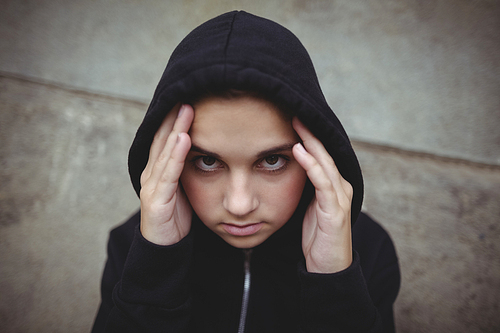 Close-up of anxious teenage girl in black hooded jacket  at school