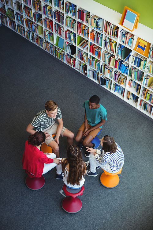 Overhead view of students interacting with each other in library at school