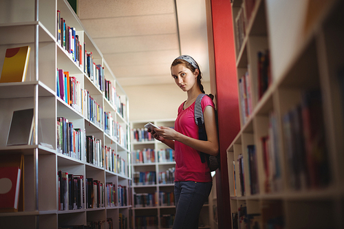 Portrait of schoolgirl using digital tablet in library at school