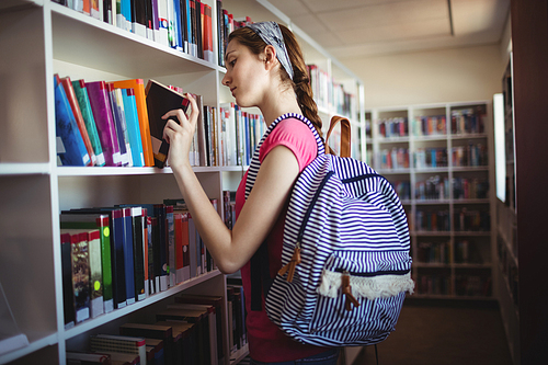 Schoolgirl selecting book in library at school