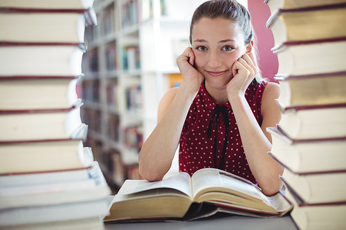 Portrait of happy schoolgirl studying library at school