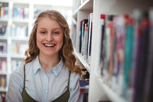 Portrait of happy schoolgirl standing in library at school