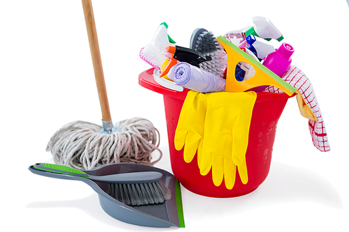 Mop and dustpan by cleaning products in bucket against white background