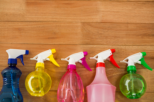 Overhead view of colorful spray bottles on wooden table