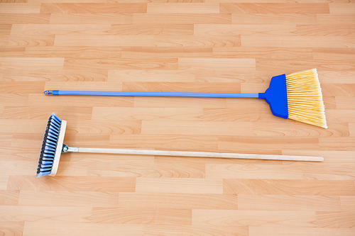 Hgh angle view of long handle brooms on hardwood floor
