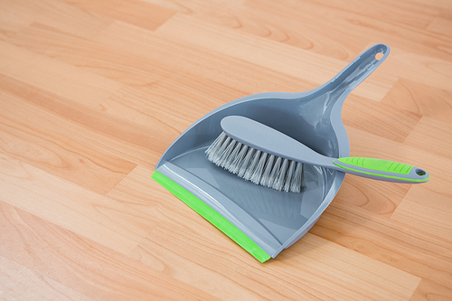 Close up of brush and dustpan on hardwood floor