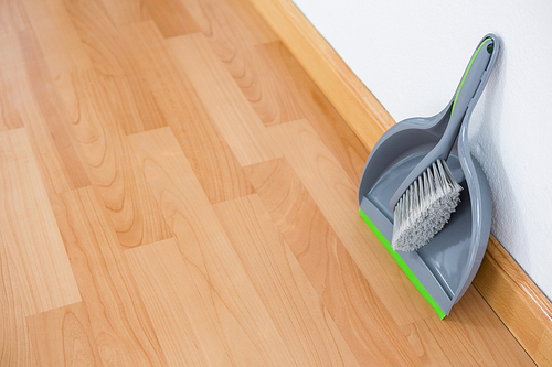 High angle view of dustpan and brush on hardwood floor against wall
