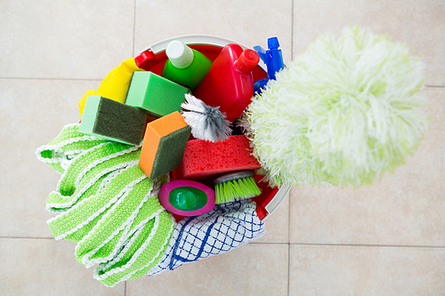 Overhead view of various cleaning products in bucket on tiled floor