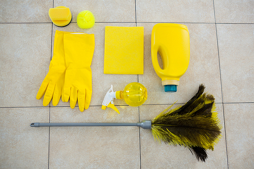 Overhead view of cleaning products and duster on tiled floor