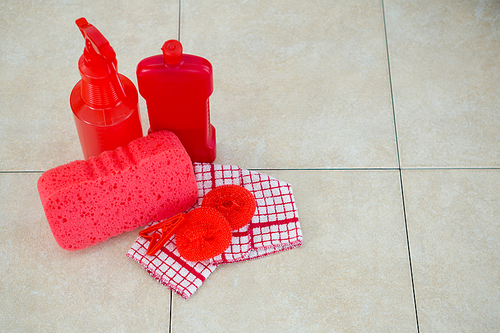 High angle view of red cleaning products with napkin on tiled floor