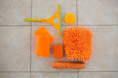 Overhead view of orange cleaning products on tiled floor