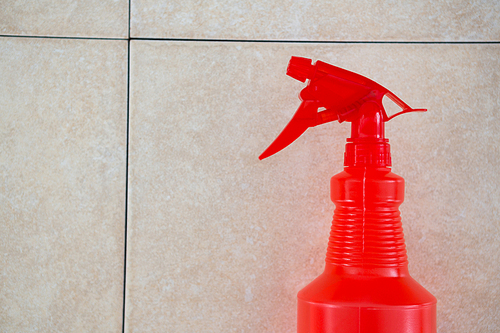 Close up red spray bottle tiled floor