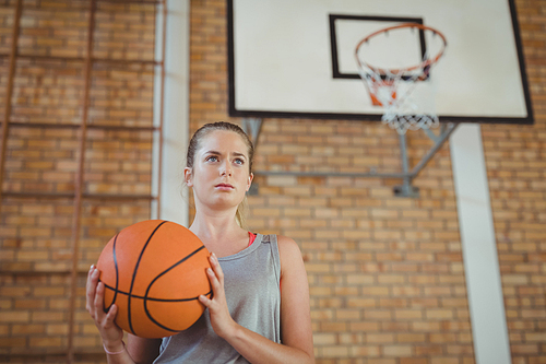 Determined girl holding a basket ball in the court