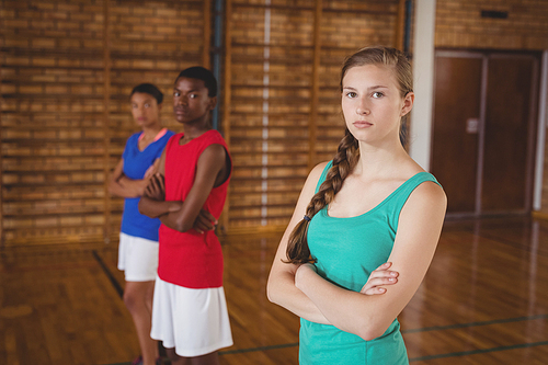 Portrait of high school kids standing with arms crossed in the basketball court