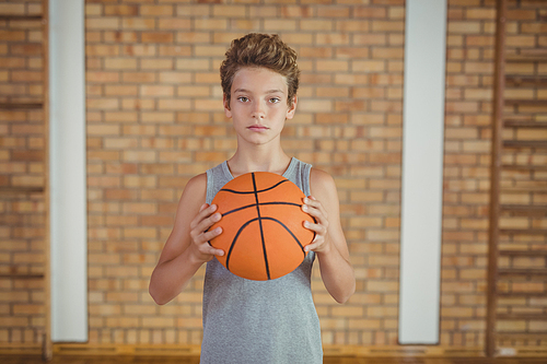 Determined boy holding a basketball in the court