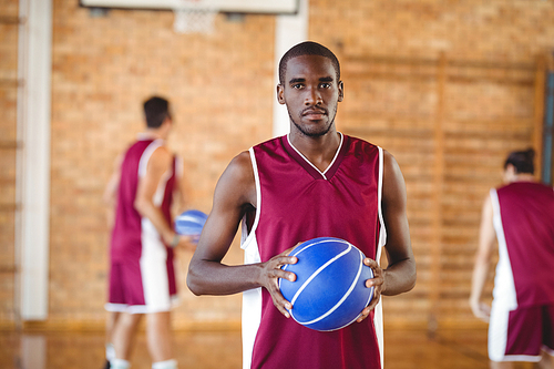 Portrait of confident basketball player holding a basketball in the court