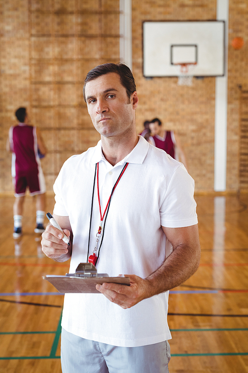 Portrait of basketball coach holding clipboard in the court