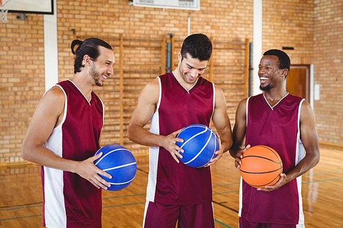 Smiling basketball players interacting with each other in the court