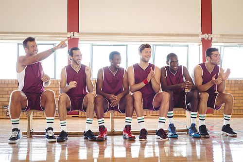 Excited basketball player sitting on bench in court