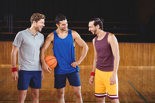Happy male basketball players laughing in basketball court