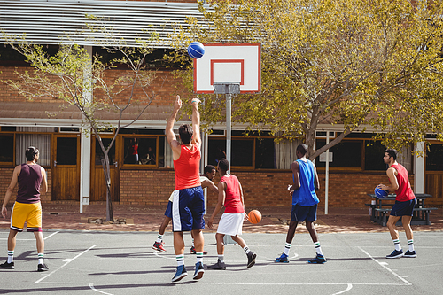 Basketball players practicing in basketball court outdoors