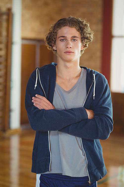 Portrait of high school boy standing with arms crossed in the sports court