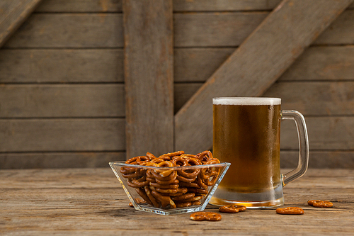 Close-up of st Patricks day mug of beer with pretzel on wooden surface