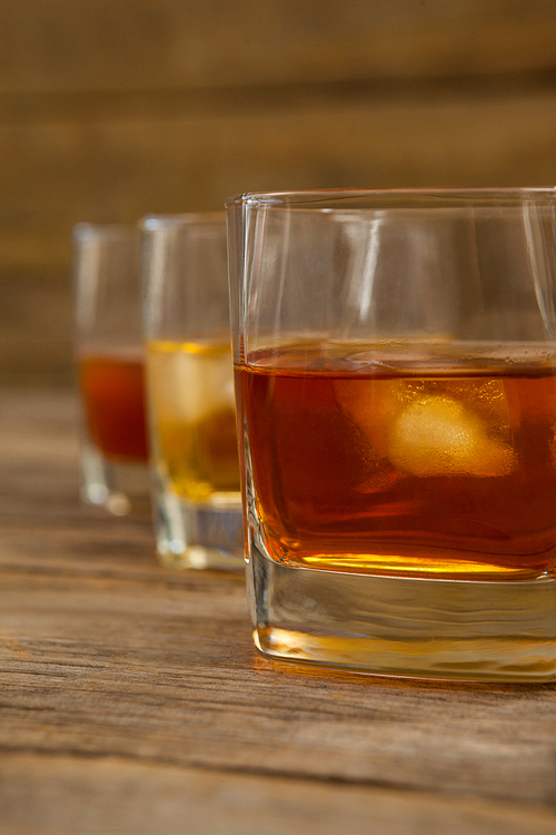 Three glasses of whiskey on wooden table