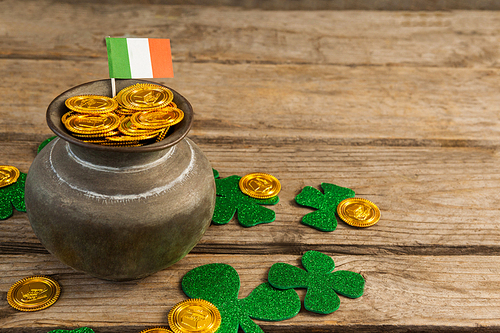 St. Patricks Day pot of chocolate gold coins with irish flag and shamrocks on wooden table