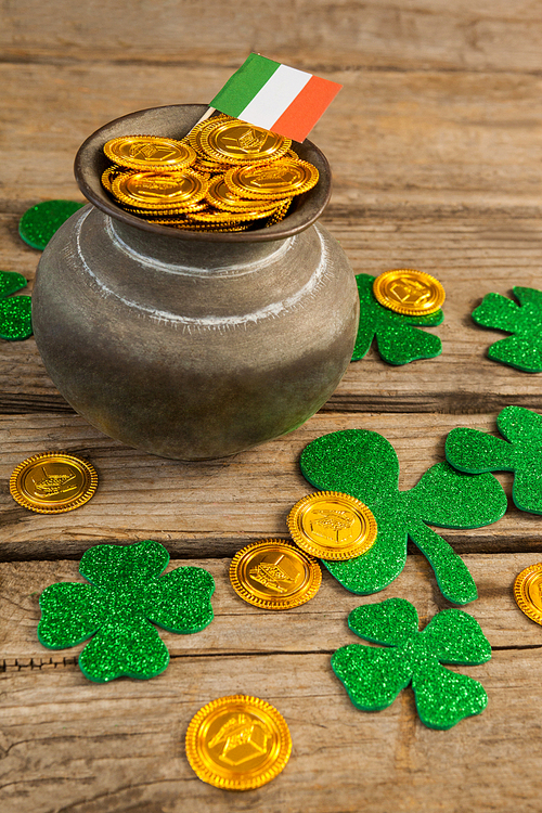St. Patricks Day pot of chocolate gold coins with irish flag and shamrocks on wooden table