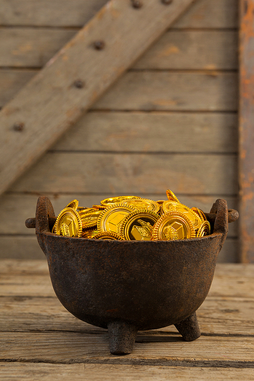 St. Patricks Day pot filled with chocolate gold coins on wooden background