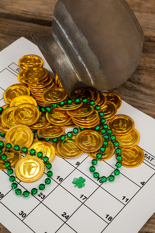 St. Patricks Day chocolate gold coins and beads kept on calendar on wooden table