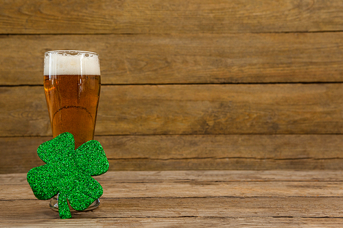 Glass of beer and shamrock for St Patricks Day against wooden background