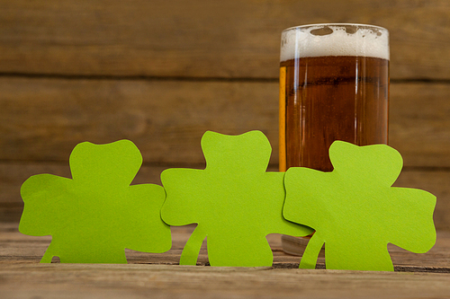 Glass of beer and shamrock for St Patricks Day against wooden background